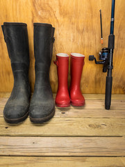 mans and boys rubber boots with  fishing rod