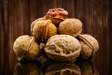 Walnut kernels and whole walnuts on rustic wooden background