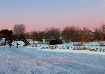 People skate at late evening on a frozen lake