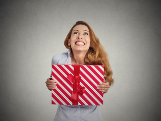 Gift box in hands of young happy woman on grey background 