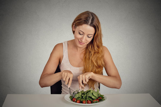 young woman eating green salad isolated grey wall background 