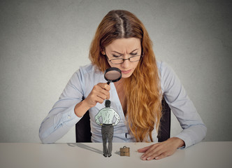 businesswoman looking at small employee through magnifying glass