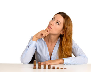 business woman sitting at table with growing stack of coins