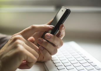 Smartphone and computer keyboard at hand.