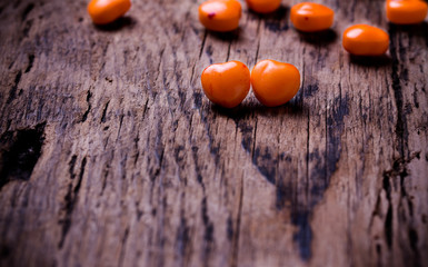 Orange, red heart shaped pills or candy on vintage wooden