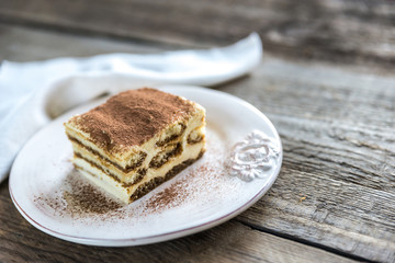 Tiramisu in the plate on the wooden background