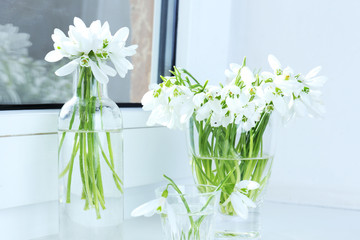 Beautiful bouquets of snowdrops in vases on windowsill