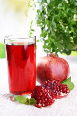 Ripe pomegranates with juice on table on light background