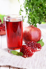 Ripe pomegranates with juice on table on light background