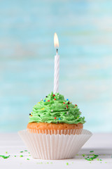 Delicious birthday cupcake on table on light blue background