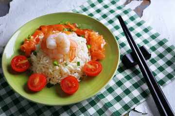 Boiled rice and shrimps, salmon on plate, on wooden background