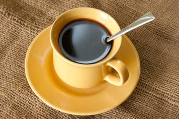 Coffee cup and saucer on a burlap texture background