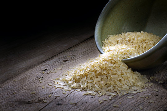 rice in a ceramic bowl on old wood, dark background