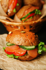 Sandwiches with salmon and vegetables on wooden background