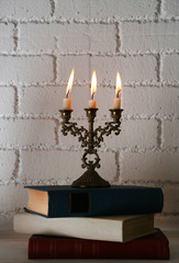 Bookshelf with books and candlestick on brick wall background