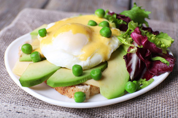 Toast with egg Benedict and avocado on plate on table close up