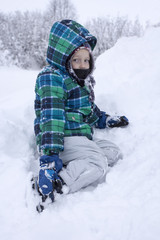 Fototapeta na wymiar Little boy having fun in the fresh snow
