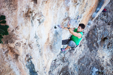 Young male rock climber struggling to make on his way up