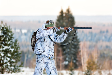 the hunter in winter camouflage shooting from a gun © rodimovpavel