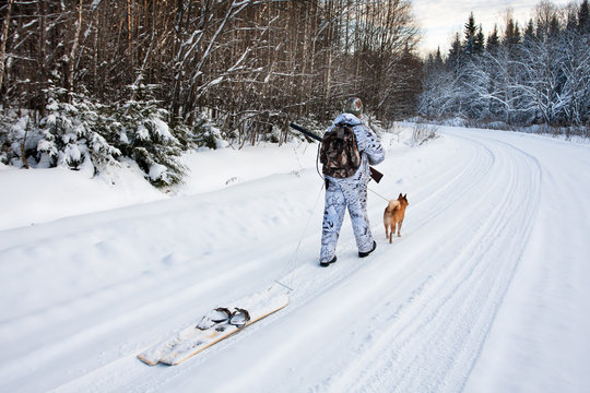 the hunter pulls the skis on winter road