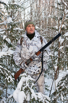 the hunter with gun in the bushes in winter