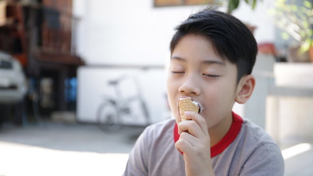 Asian kid enjoy delicious ice cream cone during the summer.