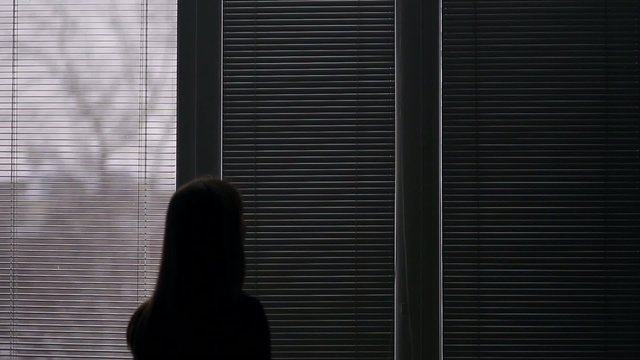 Girl opens a window blinds