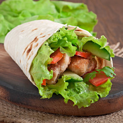 Fresh tortilla wraps with chicken nuggets and vegetables on plat