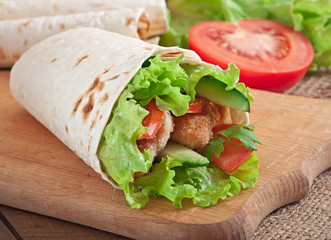 Fresh tortilla wraps with chicken nuggets and vegetables on plat