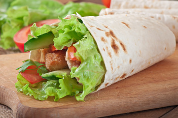 Obraz premium Fresh tortilla wraps with chicken nuggets and vegetables on plat
