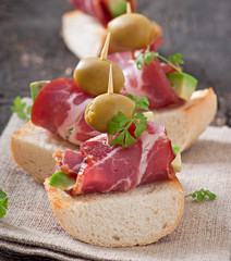 Snack on toast with ham, avocado and olives