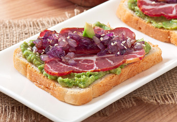 Sandwich with ham, avocado sauce and caramelized onions