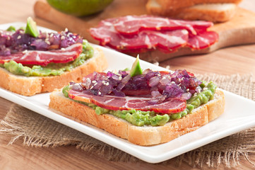 Sandwich with ham, avocado sauce and caramelized onions