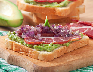 Sandwich with ham, avocado sauce and caramelized onions