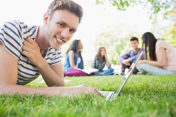 Happy student using his laptop outside