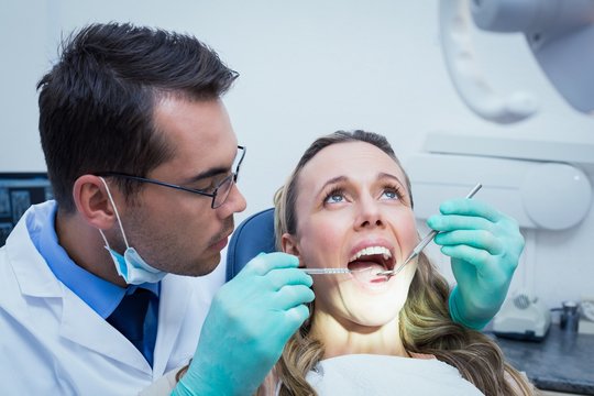 Dentist examining young womans teeth