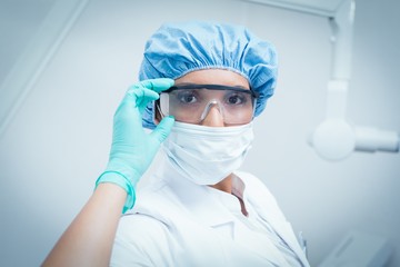 Fototapeta na wymiar Female dentist wearing surgical mask and safety glasses