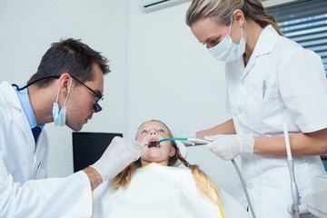 Obraz premium Dentist with assistant examining girls teeth