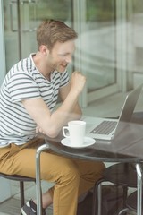 Smiling student using laptop in cafe