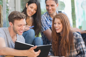 Happy students looking at book outside on campus