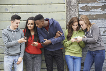 Group Of Teenagers Sharing Text Message On Mobile Phones