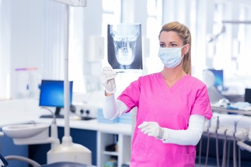 Dentist in surgical mask looking an x-ray