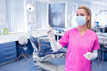 Dentist in surgical mask looking an x-ray