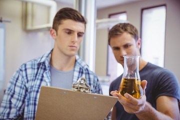 Two men looking at the beaker with beer