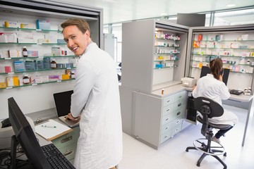 Naklejka na ściany i meble Happy pharmacist using the computer
