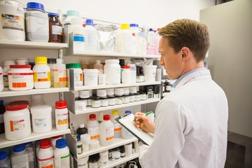 Handsome pharmacist writing on clipboard