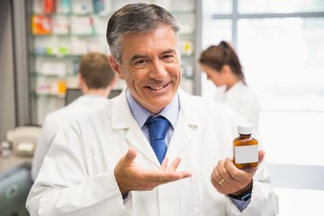 Fototapeta na wymiar Senior pharmacist showing medicine jar