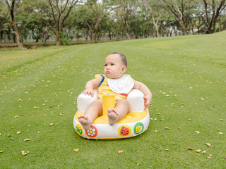 Cute Asian baby boy playing in the green grass field