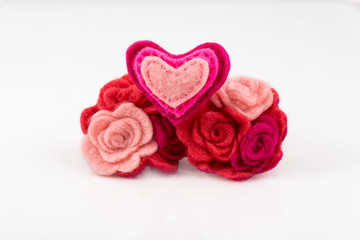 Wool heart with pink and red flowers on white background.