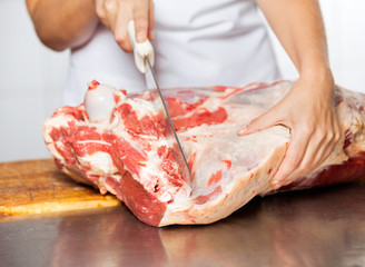 Obraz na płótnie Canvas Butcher Cutting Raw Meat At Counter